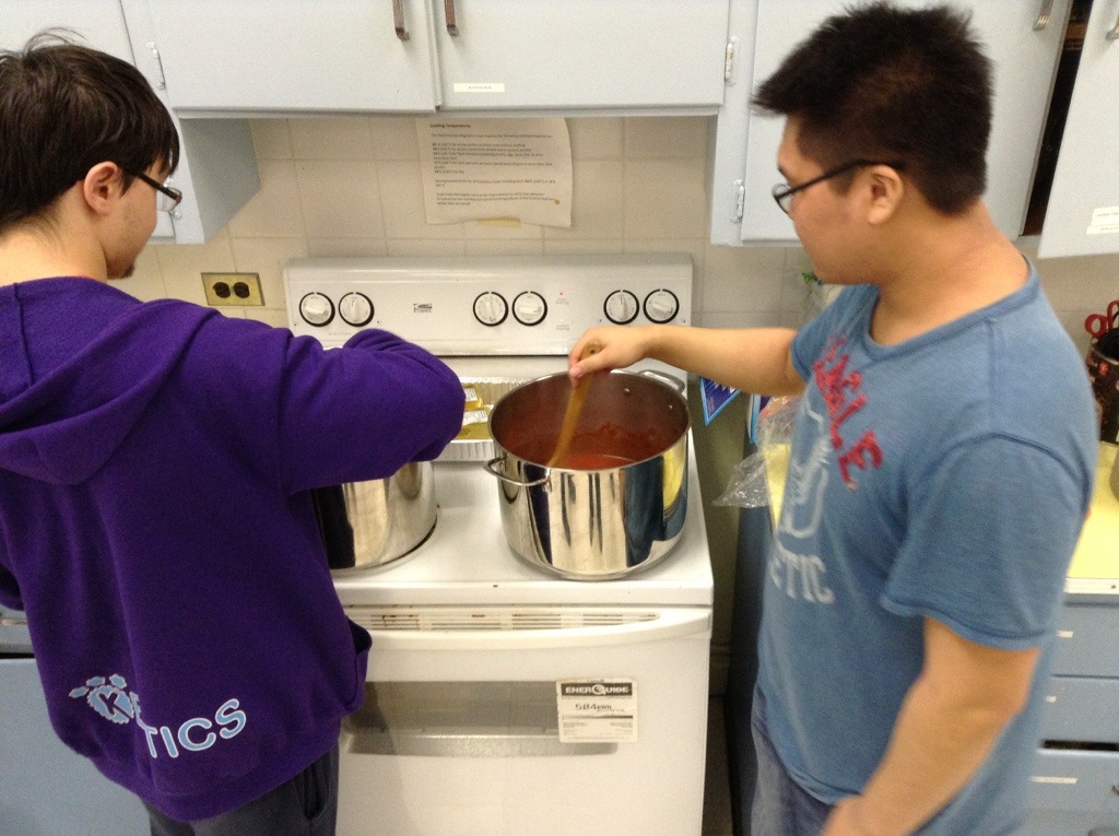 Team members stirring 2 pots of sauce